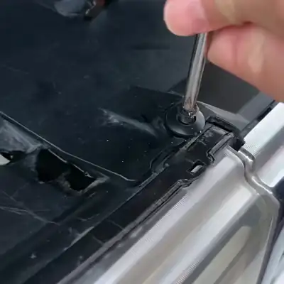 Una persona saca una grapa de tornillo de la cubierta del motor